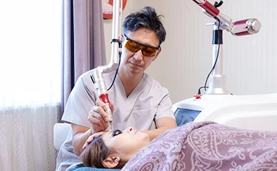 みやはらレディースクリニックの院長が、医療用レーザー治療機器を用いて患者へ施術を行っている様子。